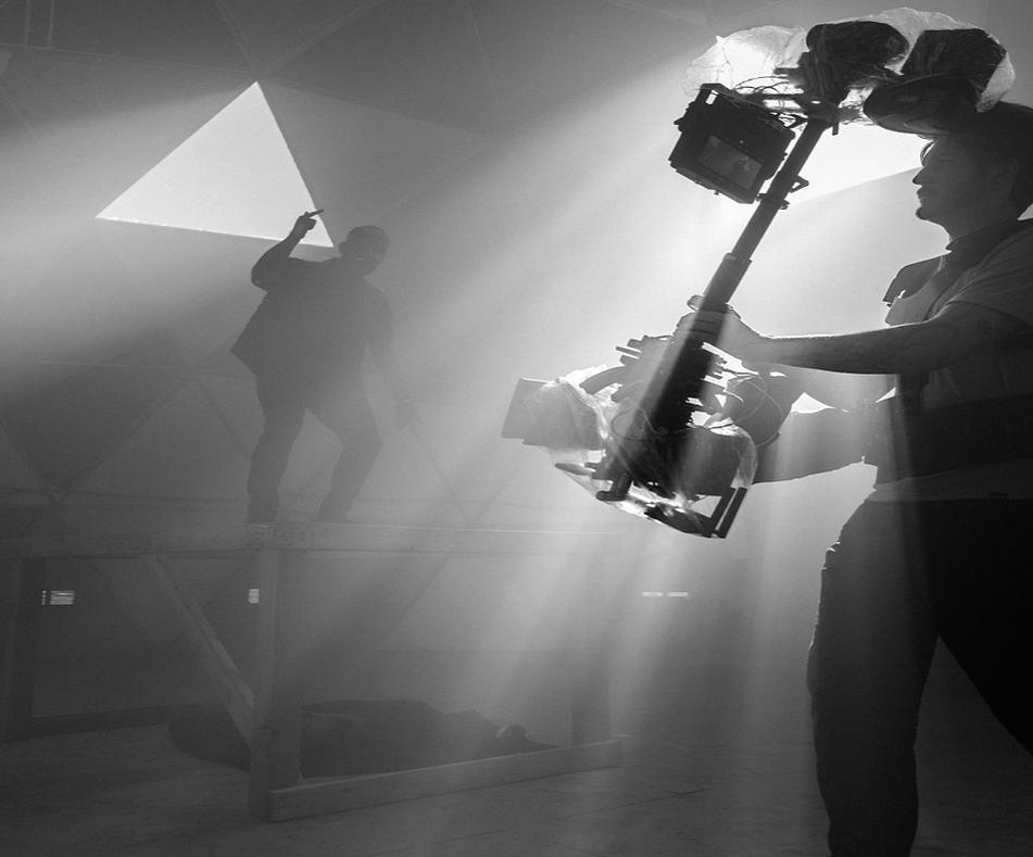 Camera operator with a stabilised rig in backlight